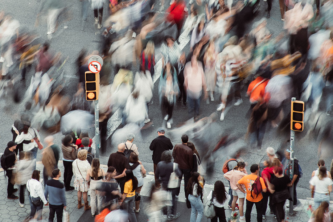 Crowd of people walking at crosswalk.